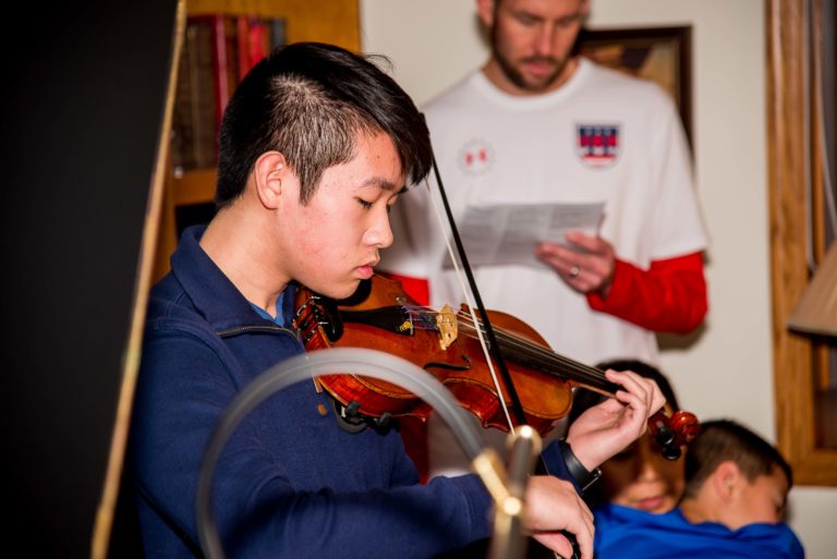 Teenage boy playing violin at music recital